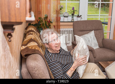 Over 80 year old grandmother sitting on a couch Stock Photo