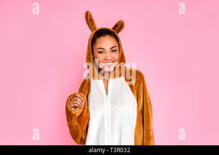 Young woman in bunny kigurumi standing isolated on pink background looking camera smiling cheerful Stock Photo