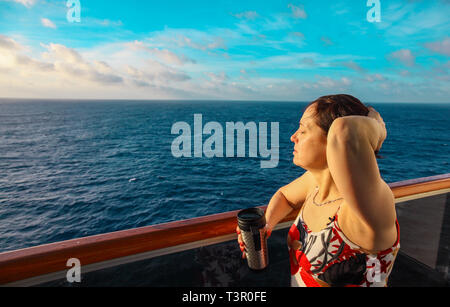 Woman on the balcony of a cruise ship at sunrise Stock Photo