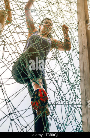 Participant in obstacle course climbing net Stock Photo