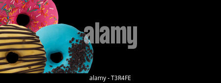 Three various donuts on a black background. Isolated Close-up. Banner. Stock Photo