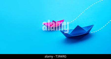 Business competition or partner concepts with two boat paper on blue worktable background.situation challenge Stock Photo