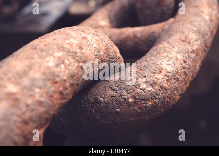 A detailed close up of rusted links in a large chain fence. Focus is on the center links with a shallow depth of field. Stock Photo