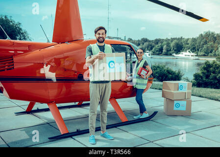 Positive cheerful guys being experienced volunteers and collecting boxes with help Stock Photo