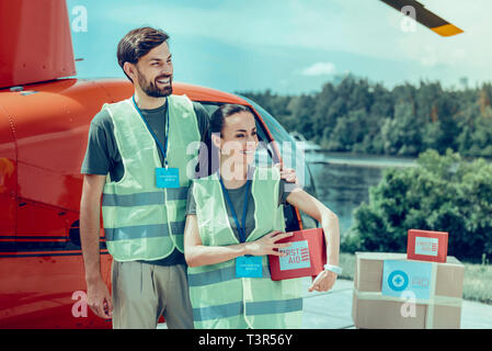 Cheerful good-looking hard-working volunteers being surrounded with boxes Stock Photo