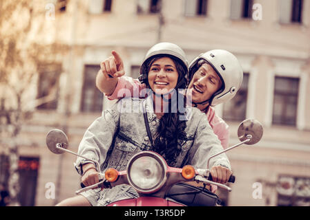 Positive cheerful man sitting behind his girlfriend Stock Photo
