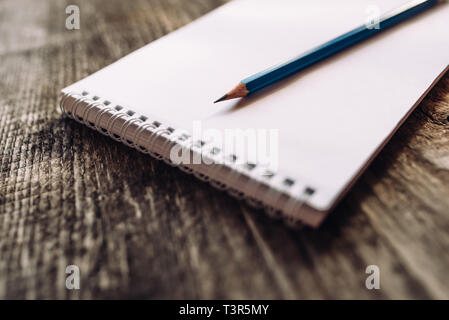 A pencil and a notebook on wooden surface close up. Stock Photo