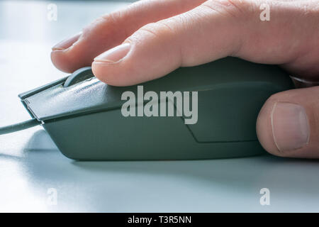 Men hand on computer mouse with white desk in the background Stock Photo