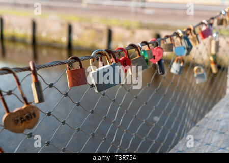 Love padlocks on railing of bridge with water in background in Holland Stock Photo