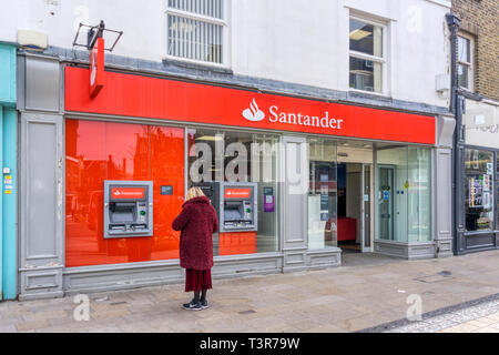 Customer using a cash machine outside a branch of Santander in Bromley Market Square, South London. Stock Photo