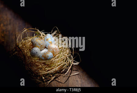 Decorative easter eggs in nest on wooden table Stock Photo