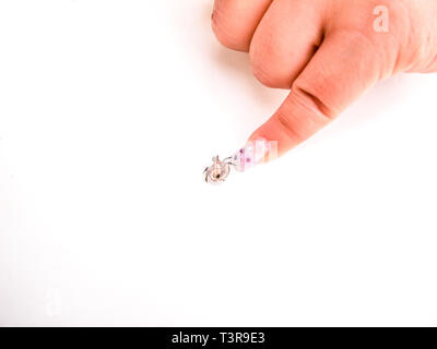 Finger with beautiful artificial nail pointing to a very small hermit crab on a white background in Mexico, with white copyspace on the left Stock Photo