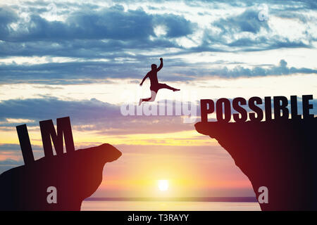 Man jumping over impossible or possible over cliff on sunset background. Business concept idea Stock Photo