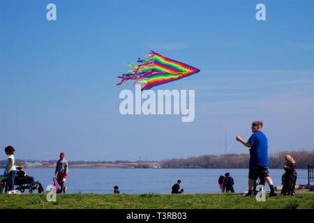 Philadelphia, PA, USA - April 6, 2019: All ages and multi-ethnicities celebrate the arrival of Spring by flying kites during an annual kite festival. Stock Photo