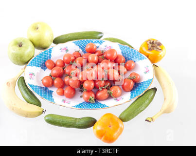 Various fresh fruits and vegetables laid on the colorful porcelain plate Stock Photo