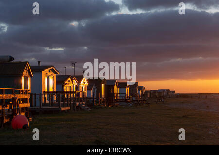 Sunset light shining on the beach huts at Seasalter, Whitstable, Kent UK. Taken during April. Stock Photo