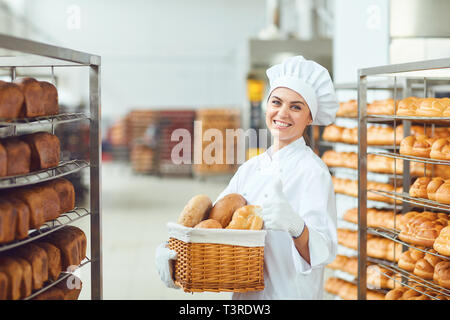 A baker woman holding a basket of baked in her hands at the bakery Stock Photo