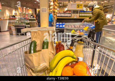 Grocery cart in supermarket filled with food products seen from the customers point of view Stock Photo