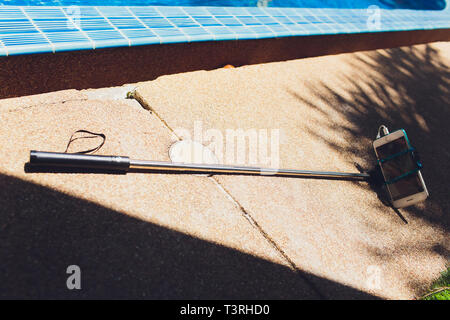 Smartphone with selfie stick, seashell lie on the seashore. Stock Photo