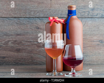 Male and female balm two glasses on a background of clay bottles of balm marked tie and a butterfly on the background of wood. Stock Photo