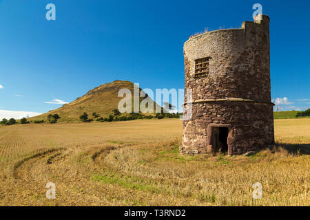North Berwick Law across a stubble field with ancient stone tower in foreground. Stock Photo