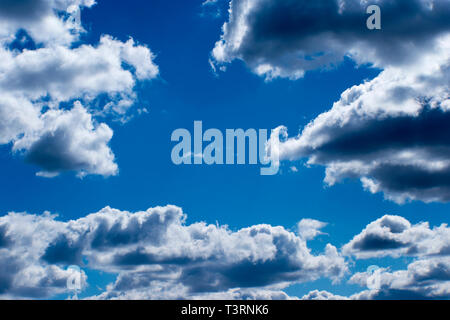 Blurred background. Blue sky and Cumulus white clouds in the contoured light of the sun. Stock Photo