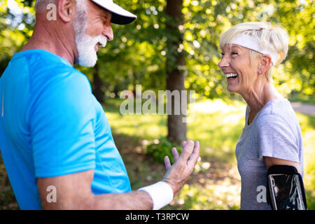 Happy fit senior couple exercising in park Stock Photo