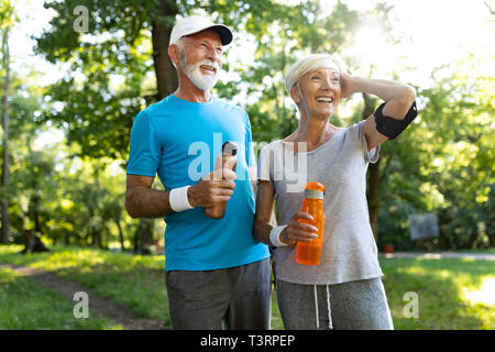 Happy fit senior couple exercising in park Stock Photo