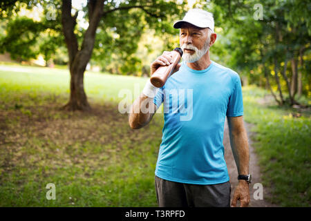 Portrait of athletic mature man after run. Handsome senior man resting after jog at the park Stock Photo