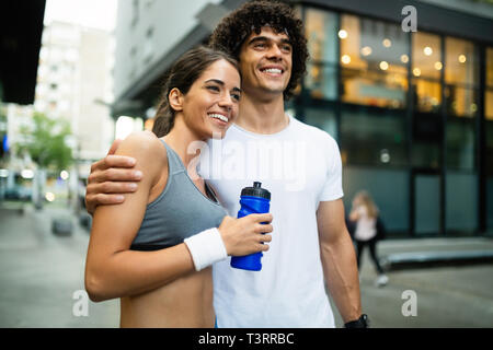 Young man and woman having break after running workout and drinking water Stock Photo