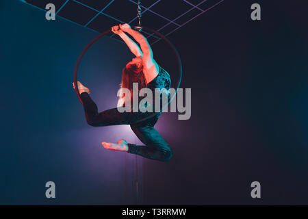 Aerial acrobat in the ring. A young girl performs the acrobatic elements in the air ring. Stock Photo