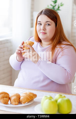 Nice plump woman holding a tasty croissant Stock Photo