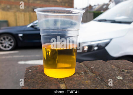 Moving car driving past a half empty plastic beaker of lager to illustrate the theme of drunk / drink driver, & driving while under the influence of alcohol. England UK (108) Stock Photo