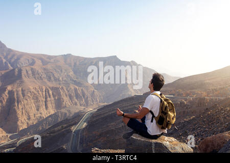 Man meditating on the mountain top at sunset Stock Photo