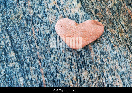 red stone heart, heart-shaped stone on dark background Stock Photo