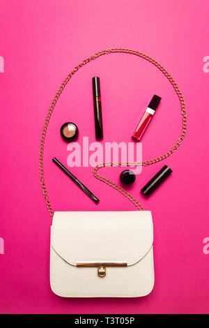 Contents of one white female bag. Female bag with copy space on pink background Stock Photo