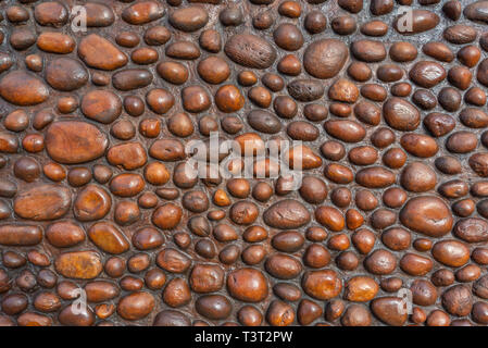 A rustic wall constructed from round polished pebbles and rocks. Stock Photo