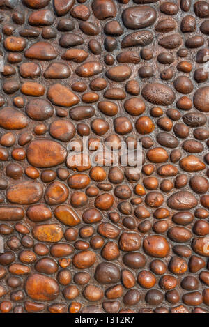 A rustic wall constructed from round polished pebbles and rocks. Stock Photo
