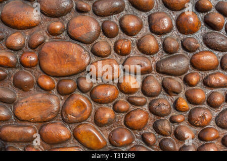 A rustic wall constructed from round polished pebbles and rocks. Stock Photo