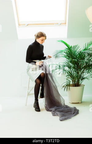 lovely seamstress,sitting on a chair and holding the grey fabric Stock Photo