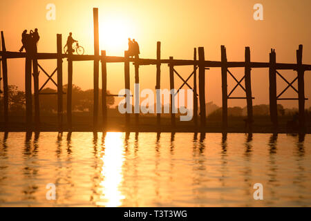 People walking on elevated wooden walkway at sunset Stock Photo