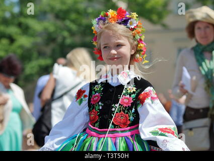 Beautiful blond Polish young girl dressed in traditional regional folk costume from Lowicz region poses during annual Corpus Christi procession. Stock Photo