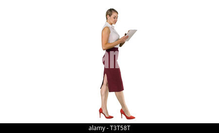 Businesswoman using electronic tab walking on white background. Stock Photo