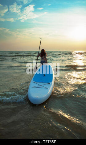 Woman pulling paddleboard in lake Stock Photo