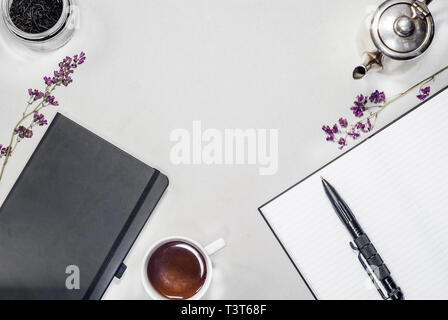 Flat composition cup with tea, silver kettle, books, pads, pen, purple dry flowers Stock Photo