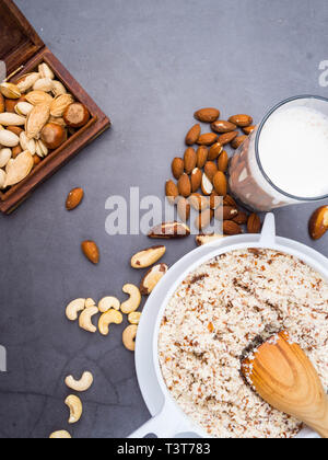 Vegan milk from nuts in glass jar with various nuts on grey background, nuts in wooden box, copy space Stock Photo