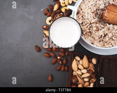 Vegan milk from nuts in glass jar with various nuts on grey background, nuts in wooden box, copy space Stock Photo