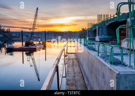 Reflection of bridge construction and sunset in still bay Stock Photo