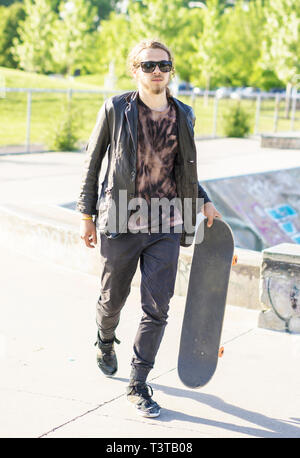 Caucasian man with beard carrying skateboard Stock Photo