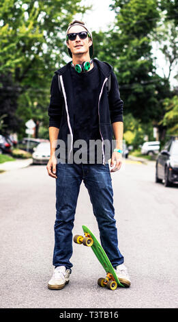 Caucasian man with headphones standing on skateboard Stock Photo